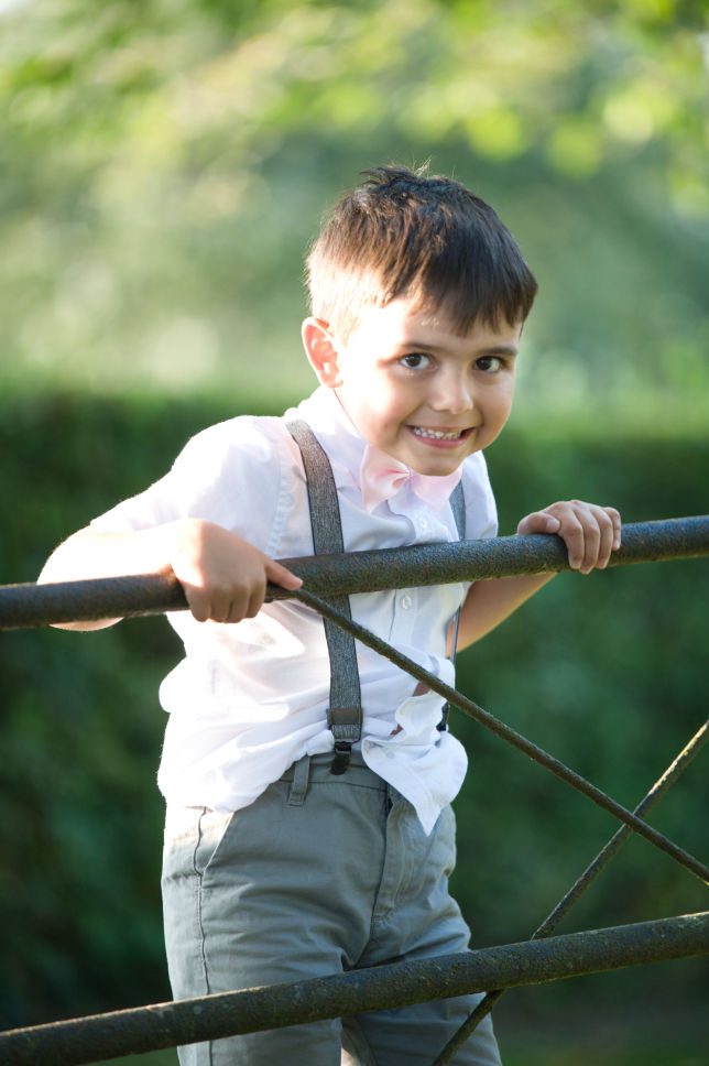 Young boy swinging on a gate at a wedding